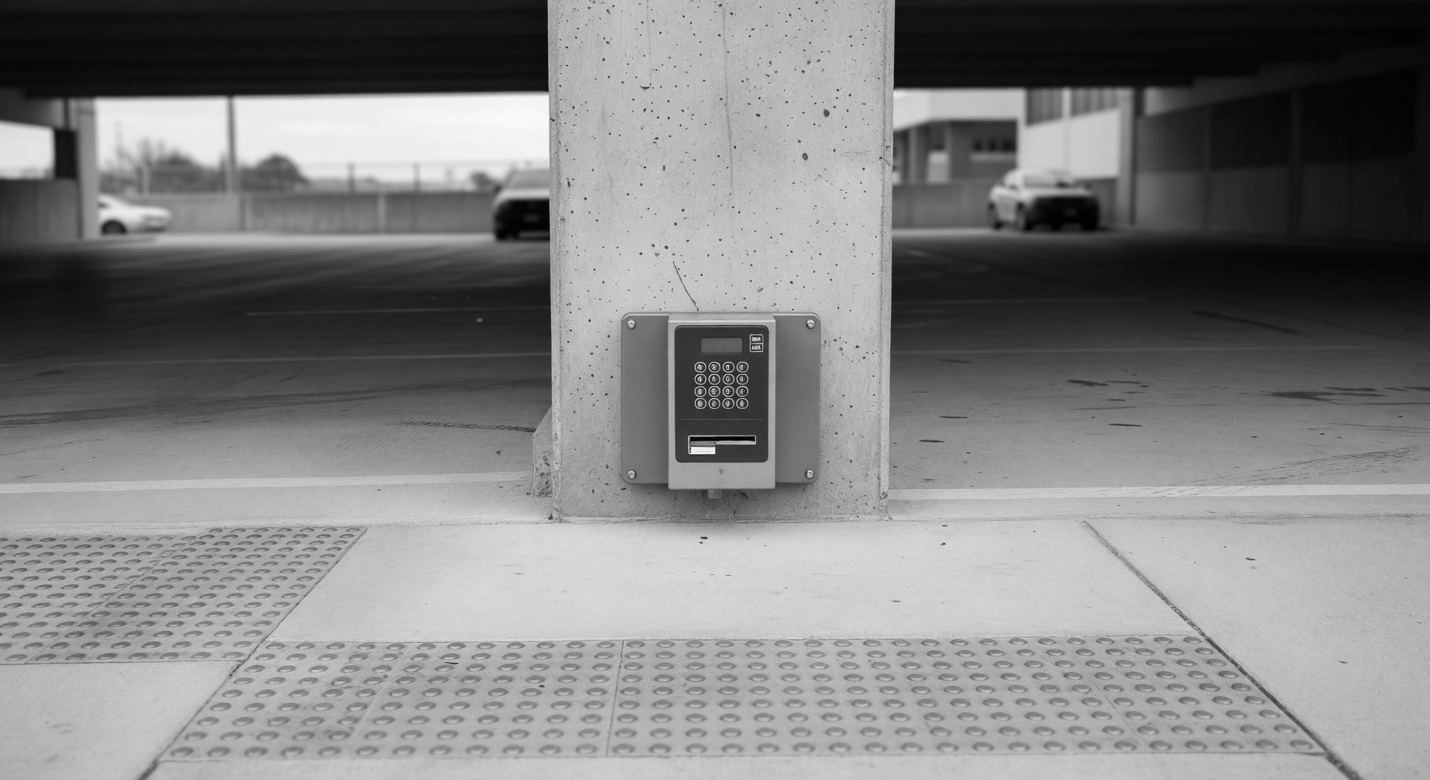 A parking gate kiosk designed with accessible reach heights and clear pavement around the operable controls