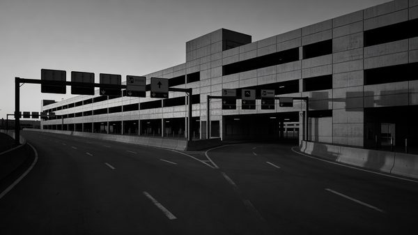 Entrance roadway of a multi-level airport parking structure at dusk