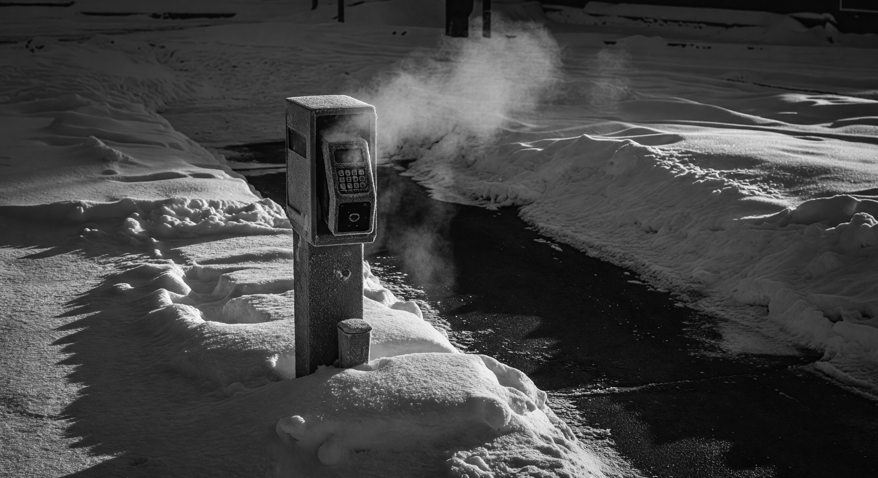 Snow-covered barrier gate housing at a parking lot entrance during winter