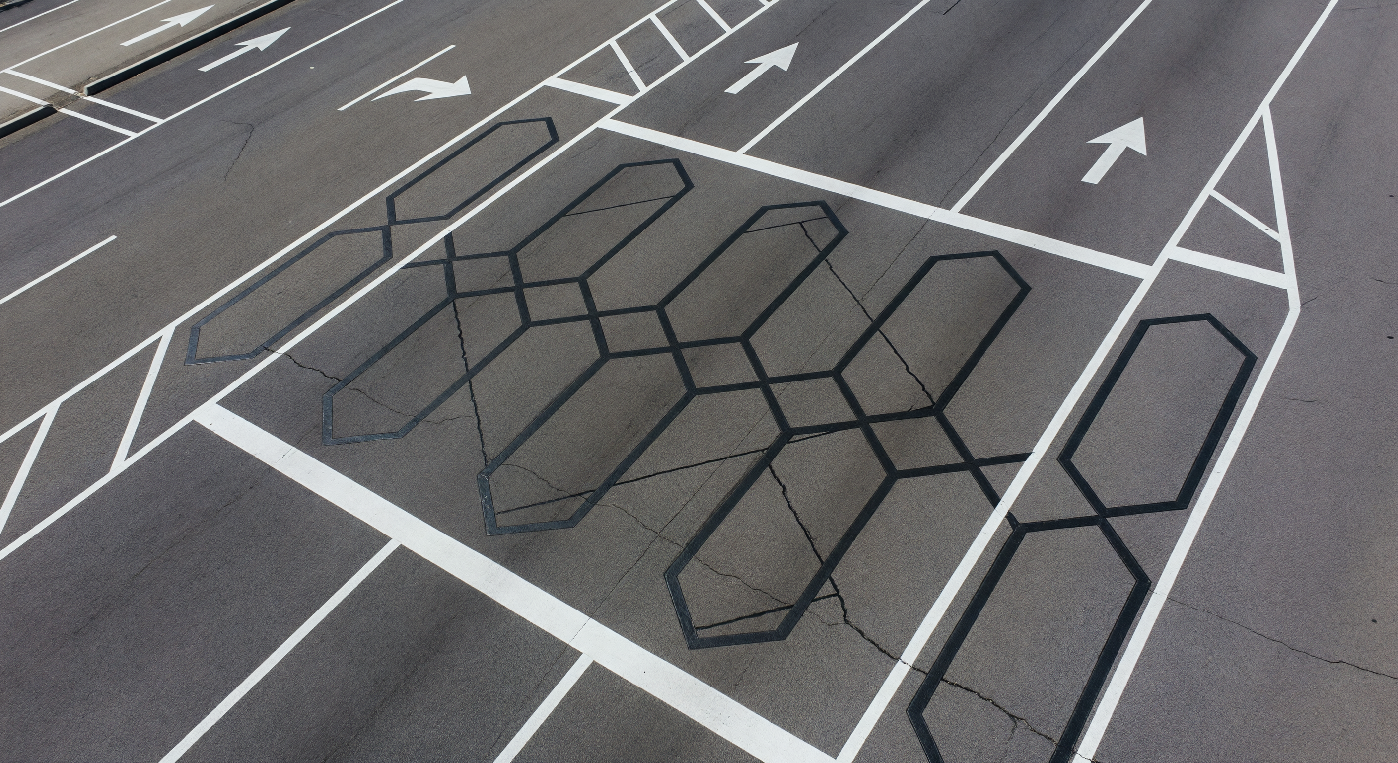 Parking lot entry with a barrier gate and inductive loops visible in the pavement
