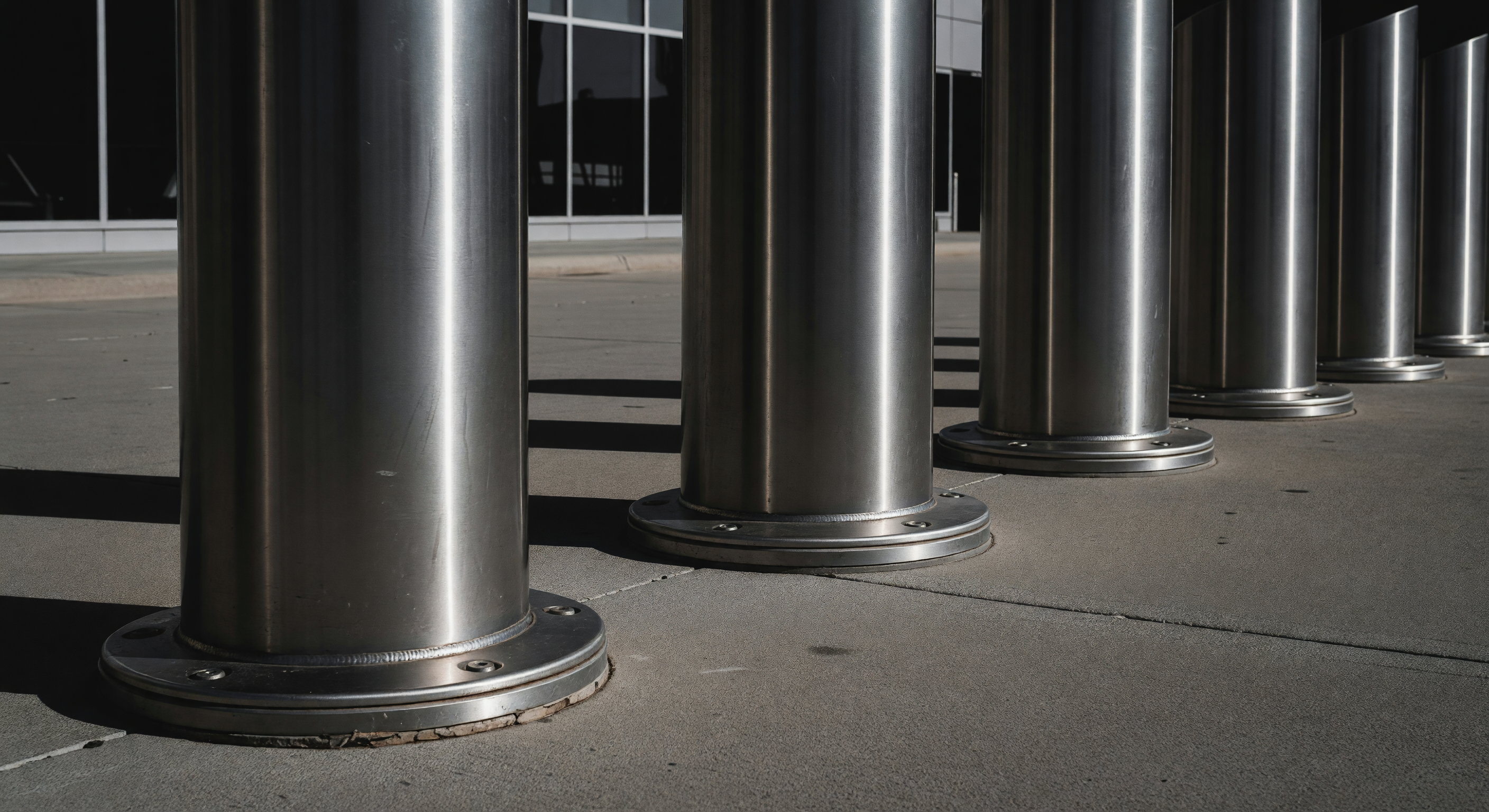 A commercial entry lane with retractable bollards positioned ahead of a rising parking barrier gate arm