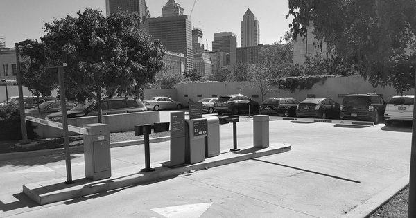 Parking lot barrier arm beside a ticket dispensing machine