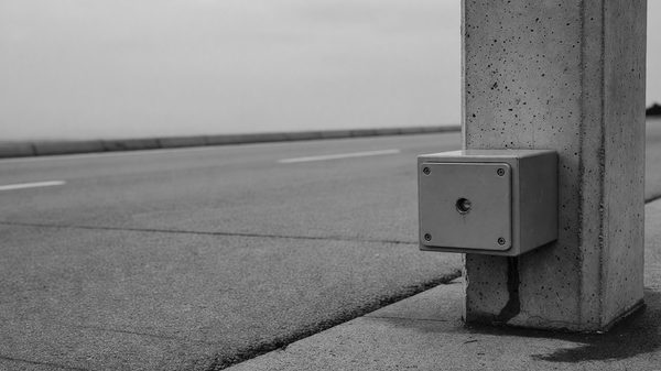 Close-up of a photo eye sensor and contact safety edge mounted on a barrier gate housing