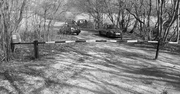 Barrier gate across a gravel parking area access road