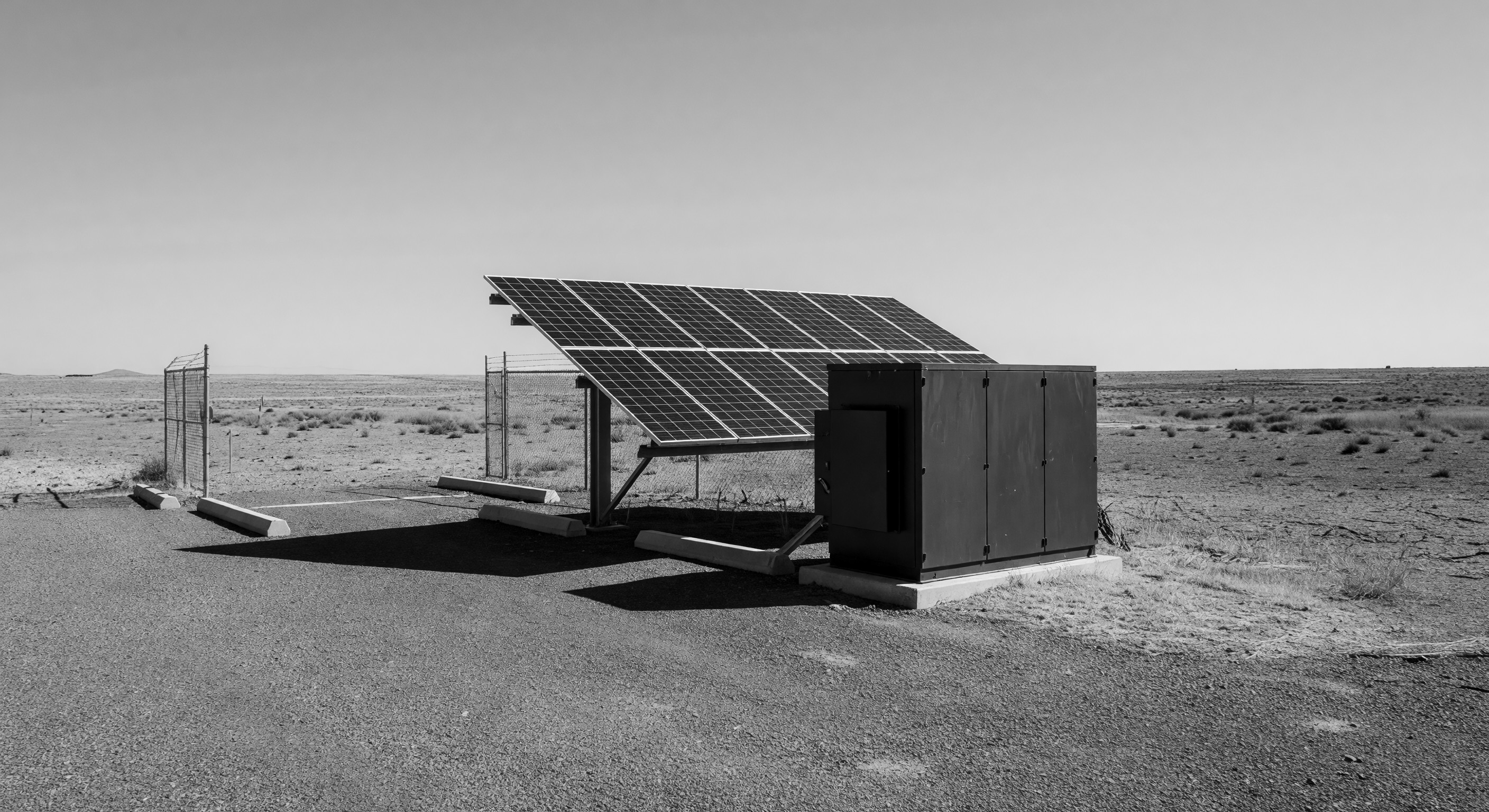 A solar-powered barrier gate at a remote parking facility with a photovoltaic panel mounted on the gate cabinet and battery enclosure